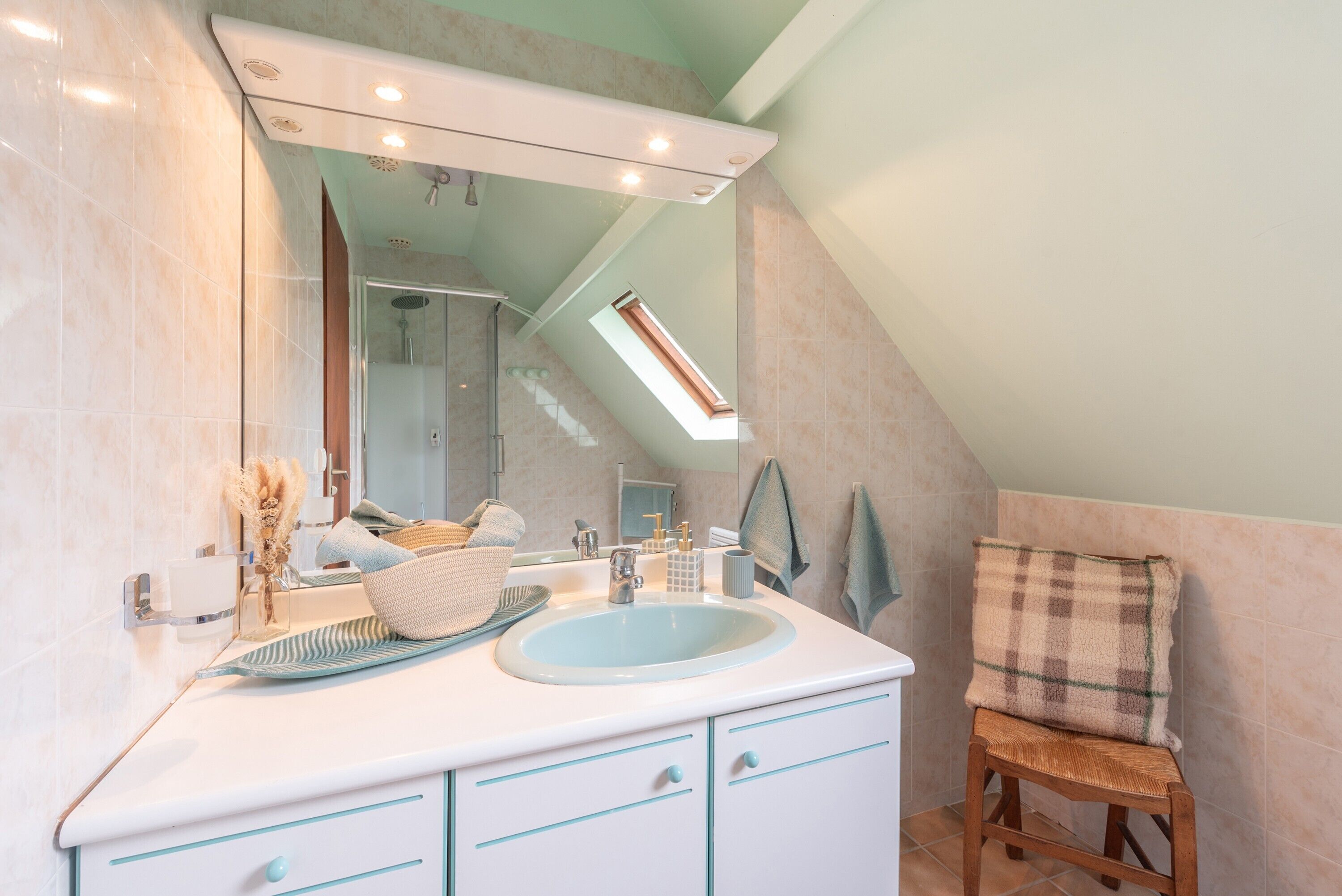 Ein Badezimmer mit Dachfenster, Waschbecken und Spiegel.