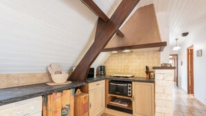 A kitchen with a built-in oven, a microwave, and a coffee maker. There is a wooden cabinet and a countertop.