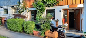 Un bâtiment à la façade en bois, une moto garée devant, et une enseigne indiquant « Schaumann's Hüs ».