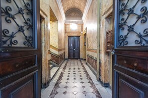 A hallway with a patterned floor, a double door, and a staircase.