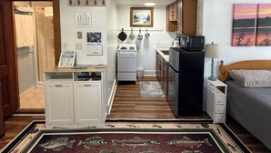 A compact kitchen with a stove, refrigerator, and microwave. - Sebago Lake studio-style condo with enclosed sunroom and sunset views (Standish)