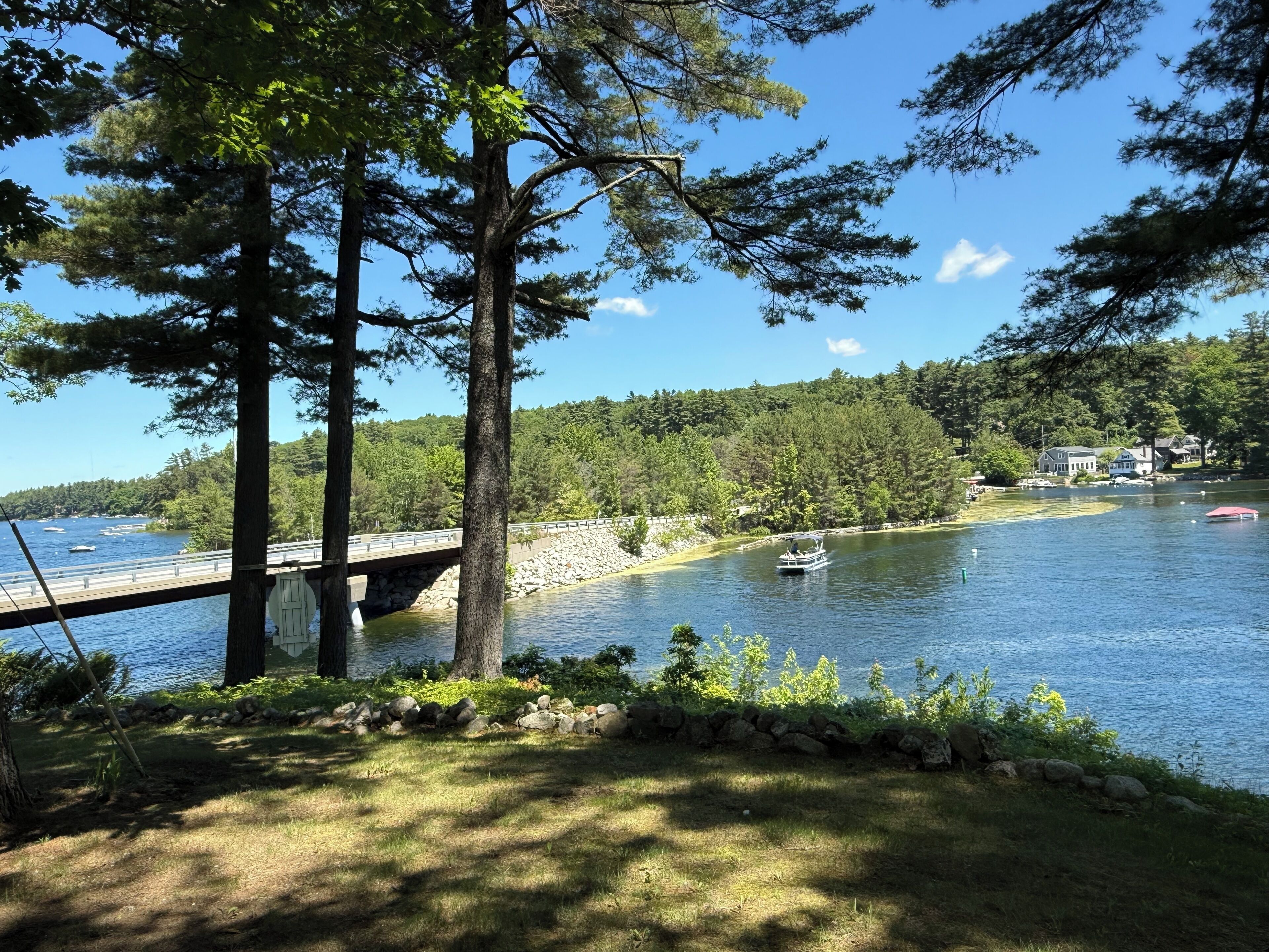 A lake with boats, a bridge, and houses in the background.