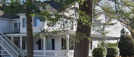 A two-story white house with a covered porch and a staircase leading to the second floor.
