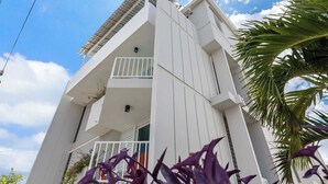Un bâtiment moderne de couleur blanche, doté d’un balcon et d’une petite fenêtre.
