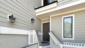 A two-story house with a front porch, a staircase, and two exterior wall-mounted lanterns.
