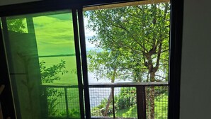 A room with a large window overlooking a lush green landscape and a body of water. - Bohol-Lahoy Dive & Beach Resort (Guindulman)