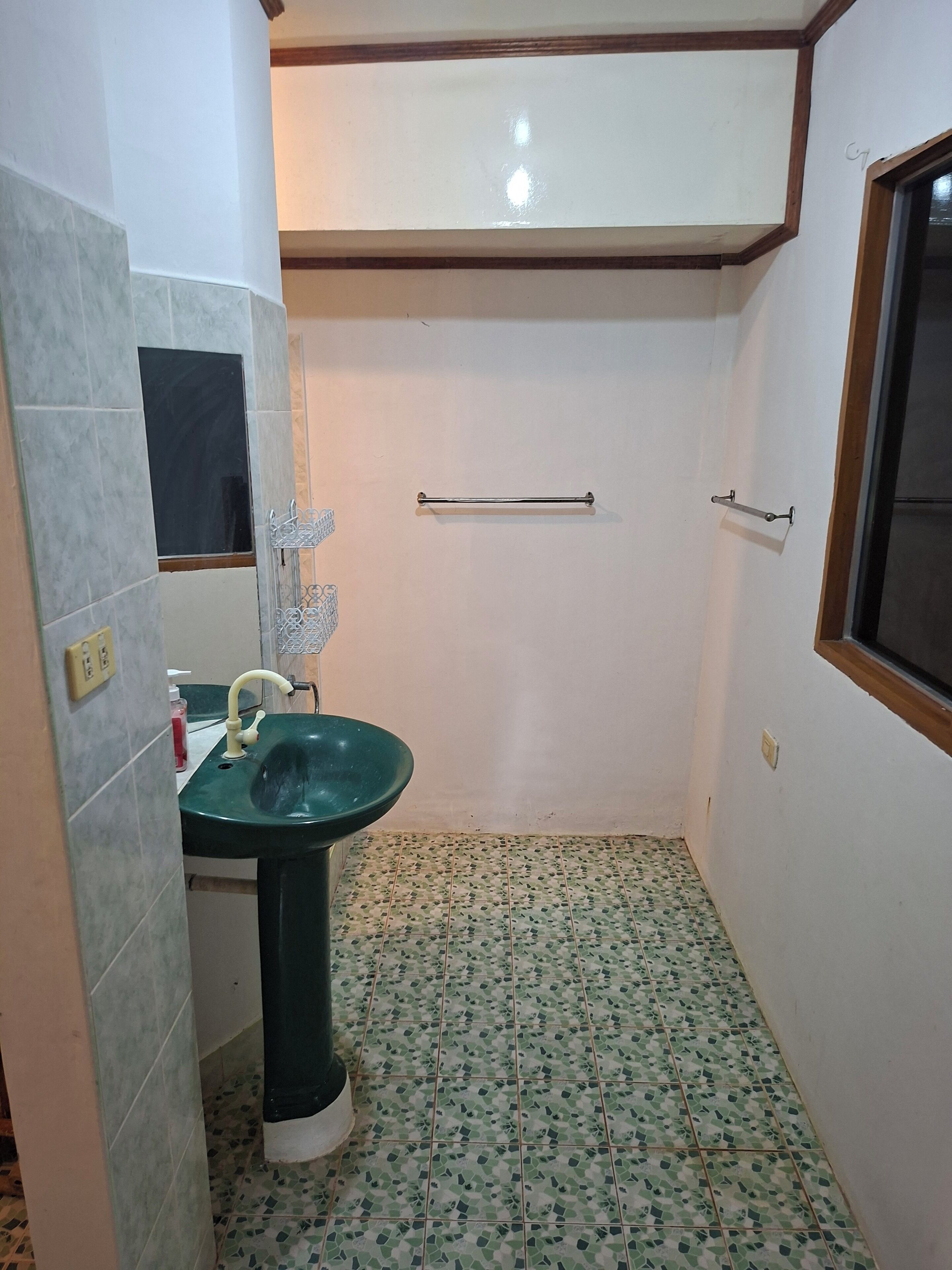 A small bathroom with a green sink, a mirror, and a window.