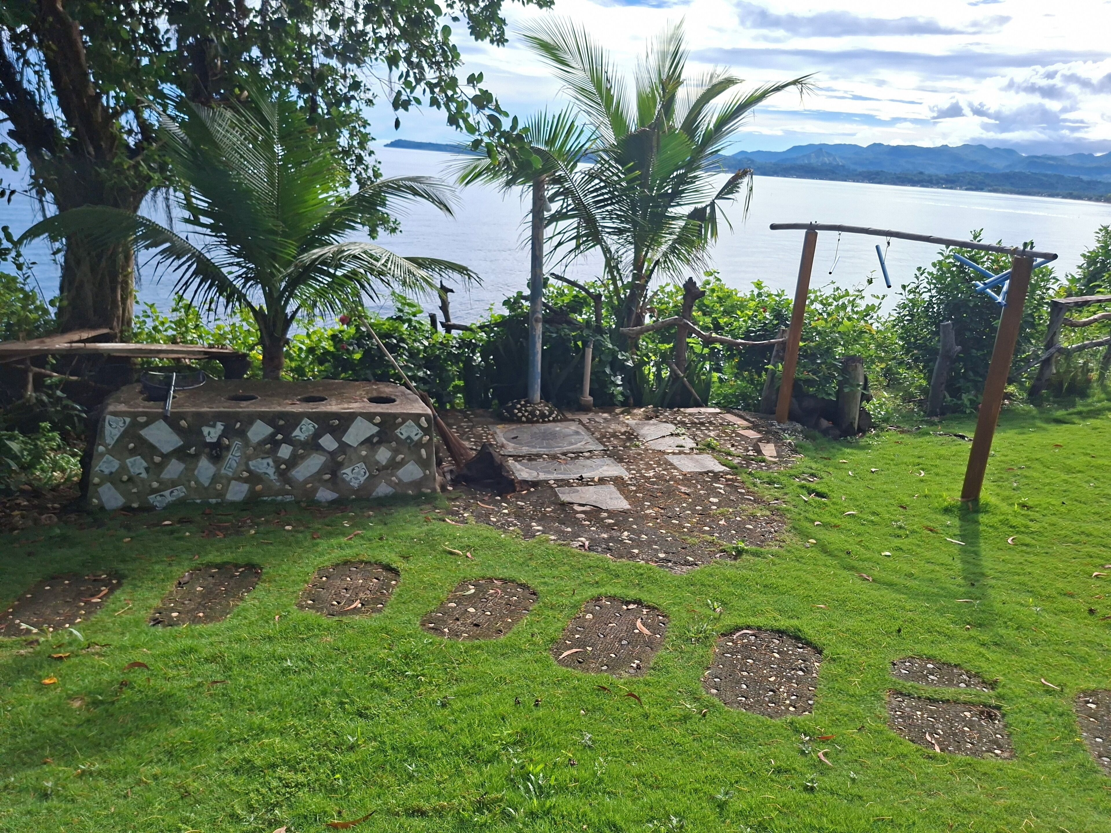 A garden with a stone bench, a small pond, and a view of a lake.