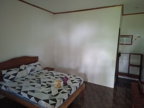 A bedroom with a bed, a wooden headboard, a small bedside table, and a wall-mounted heater.