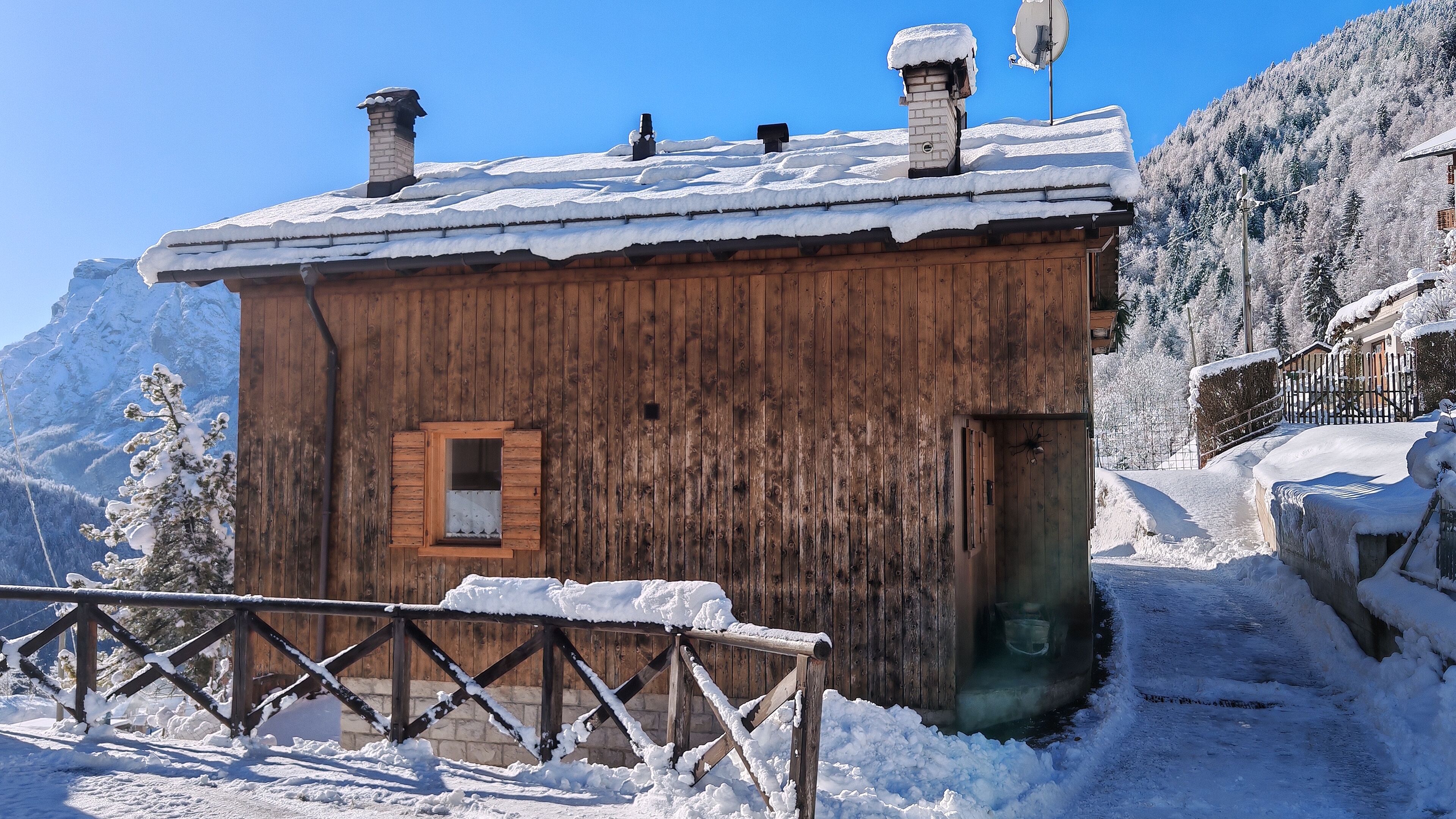 Une cabane en bois, dont le toit est recouvert de neige, avec une petite fenêtre et une porte.