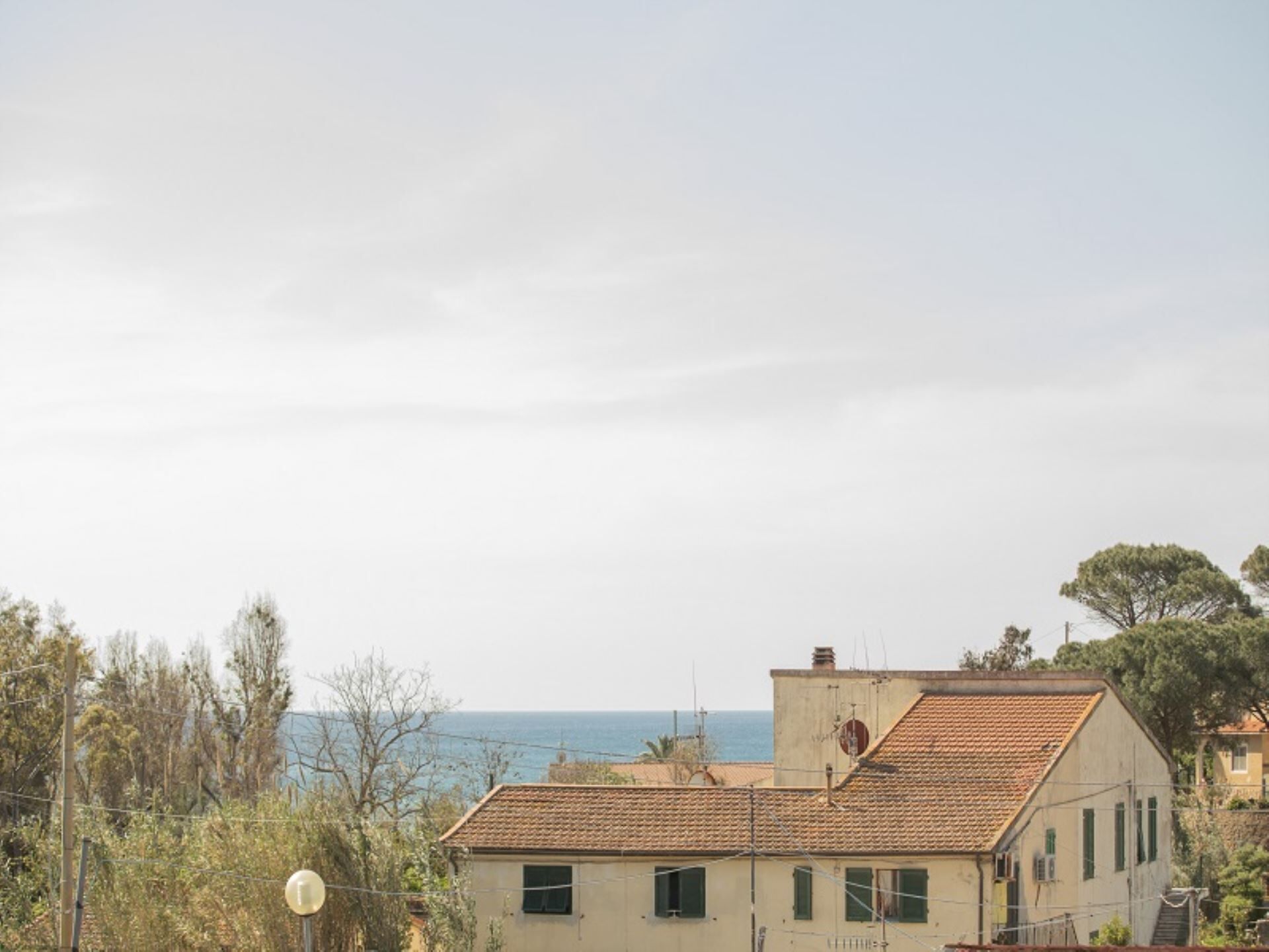 A coastal building with a tiled roof, a visible satellite dish, and a clear view of the sea in the background.