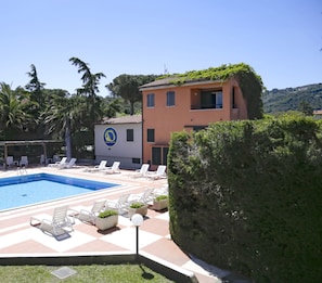 Une piscine avec des chaises longues et un bâtiment orné d’un logo.