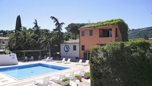 A swimming pool with lounge chairs and a building with a logo. - The apartments, all studios, are simply and functionally furnished and all consist of a living room (Marina di Campo)