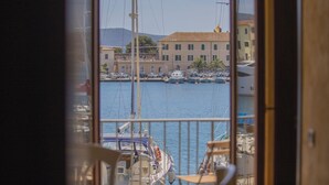 A view of a marina with boats docked, a building with a tiled roof, and a clear sky. - Tastefully furnished, it consists of a family room with a double bed and a single bed, a small livin (Portoferraio)