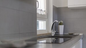 A modern kitchen with a sleek countertop, a stainless steel faucet, and a window with blinds.