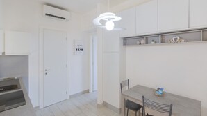 A modern kitchen with white cabinets, a dining area with a table and chairs, and a sign that reads "HOME Sweet HOME".
