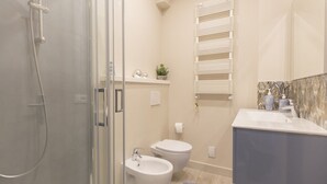 Ein modernes Badezimmer mit einer Duschkabine aus Glas, einer weißen Toilette, einem Waschbecken und einem Handtuchhalter.