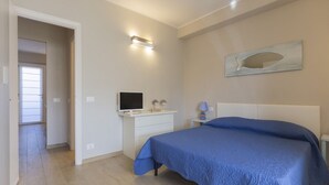 Ein Schlafzimmer mit einem Bett, einem Fernseher, einem Nachttisch und einer Wandleuchte.