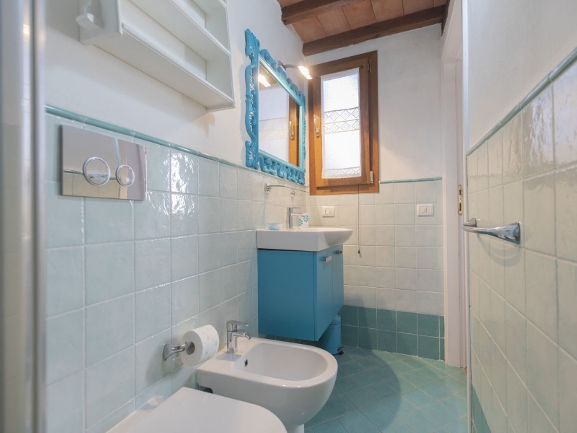 A bathroom with a white toilet, a blue sink, and a mirror above the sink.
