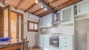 A kitchen with wooden beams, a stove, oven, and a refrigerator. - A short distance from the center of Rio Marina, easily reachable on foot, we offer our clients a cha (Rio Marina)