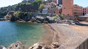 A coastal town with a prominent clock tower, rocky shoreline, and terraced buildings. - A short distance from the center of Rio Marina, easily reachable on foot, we offer our clients a cha (Rio Marina)