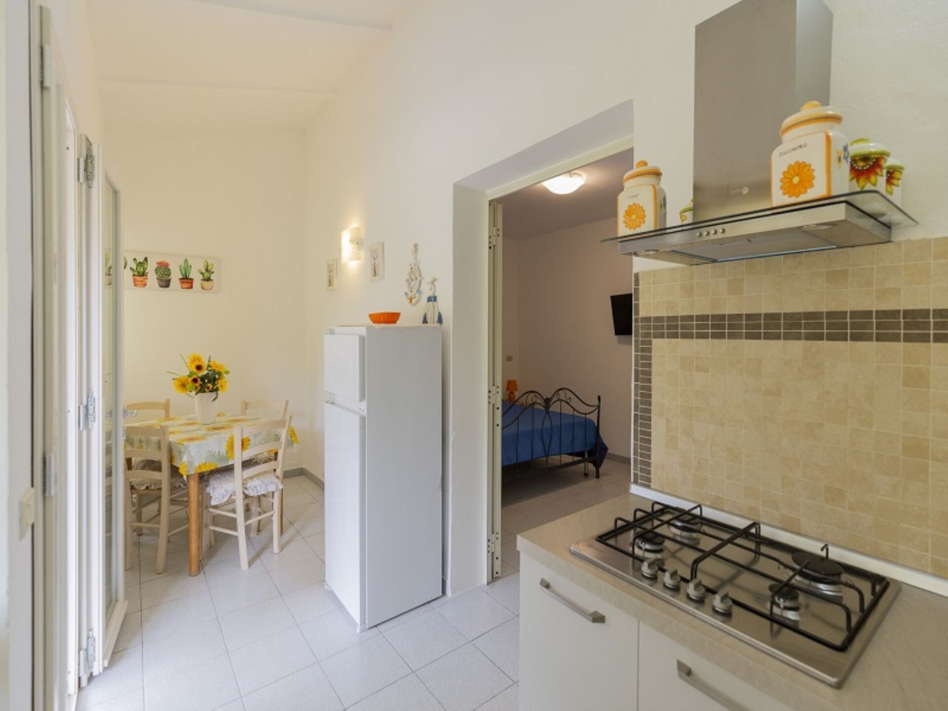 A compact kitchen with a gas stove, a refrigerator, and a dining area with a table and chairs.