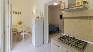 A compact kitchen with a gas stove, a refrigerator, and a dining area with a table and chairs.
