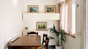 Ein Essbereich mit einem Holztisch, Stühlen, einem Blumentopf und drei gerahmten Bildern an der Wand.