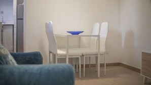 Una cocina pequeña y moderna con armarios blancos y un refrigerador blanco.