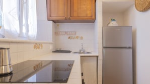 Una cocina con azulejos blancos, armarios de madera, un refrigerador de acero inoxidable y un lavamanos.