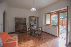 A kitchen with a dining table and chairs, a hanging light fixture, and a view of the outside.