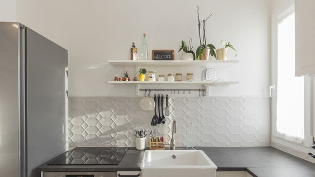 Eine moderne Küche mit einem Edelstahl-Kühlschrank, einer schwarzen Induktionskochplatte, einer weißen Spüle und einer Rückwand mit Fischgrätmuster.