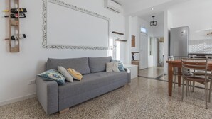 Ein modernes Wohnzimmer mit einem grauen Sofa, einer Holzkommode und einem Essbereich mit Holztisch und -stühlen.