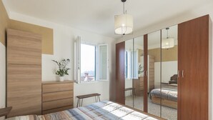Ein Schlafzimmer mit einem Bett, einem Holzschrank, einem kleinen Tisch und einem Blumentopf.