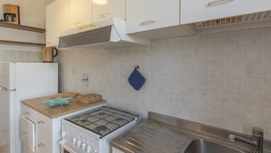A modern kitchen with white cabinets, a gas stove, a built-in oven, a stainless steel sink, and a coffee machine on the countertop. - It is located on the ground floor of a building consisting of three terraced houses. ' It consists o (Capoliveri)