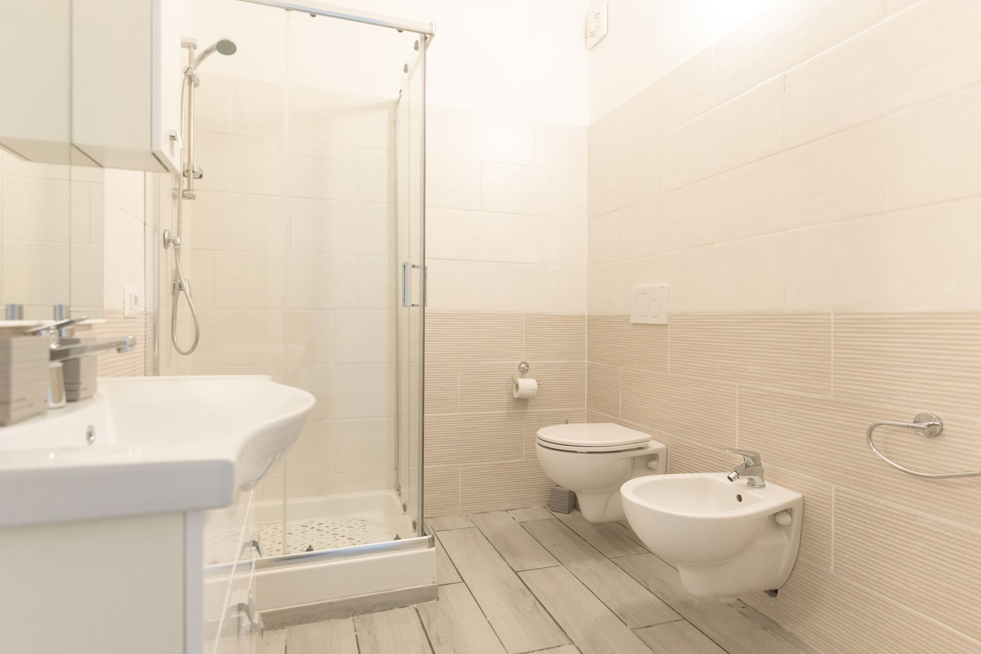 Une salle de bain moderne équipée d’une douche, de toilettes, d’un bidet et d’un lavabo.