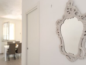 Ein weißer, aufwendig verzierter Spiegel mit dekorativem Rahmen an einer Wand.