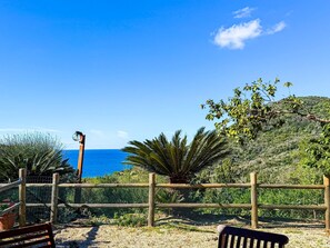 A coastal view with a wooden fence, a bench, and a clear blue sky.