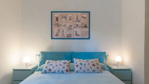Une chambre à coucher avec un lit, deux tables de chevet, deux lampes et un collage encadré accroché au mur.