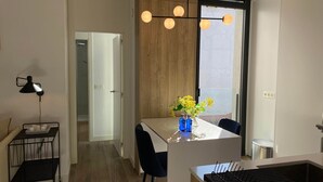 A modern kitchen with a central island, black chairs, a hanging light fixture, and a window with a view. - w Dreamy 1BR With Terrace in Chueca (Madrid)