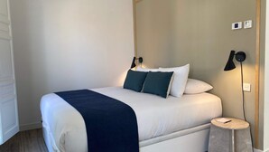 A modern bedroom with a large bed, bedside lamps, a small round table, and a wall-mounted thermostat. - w Dreamy 1BR With Terrace in Chueca (Madrid)