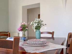 A dining table with a floral centerpiece, a stack of plates, and a menu.