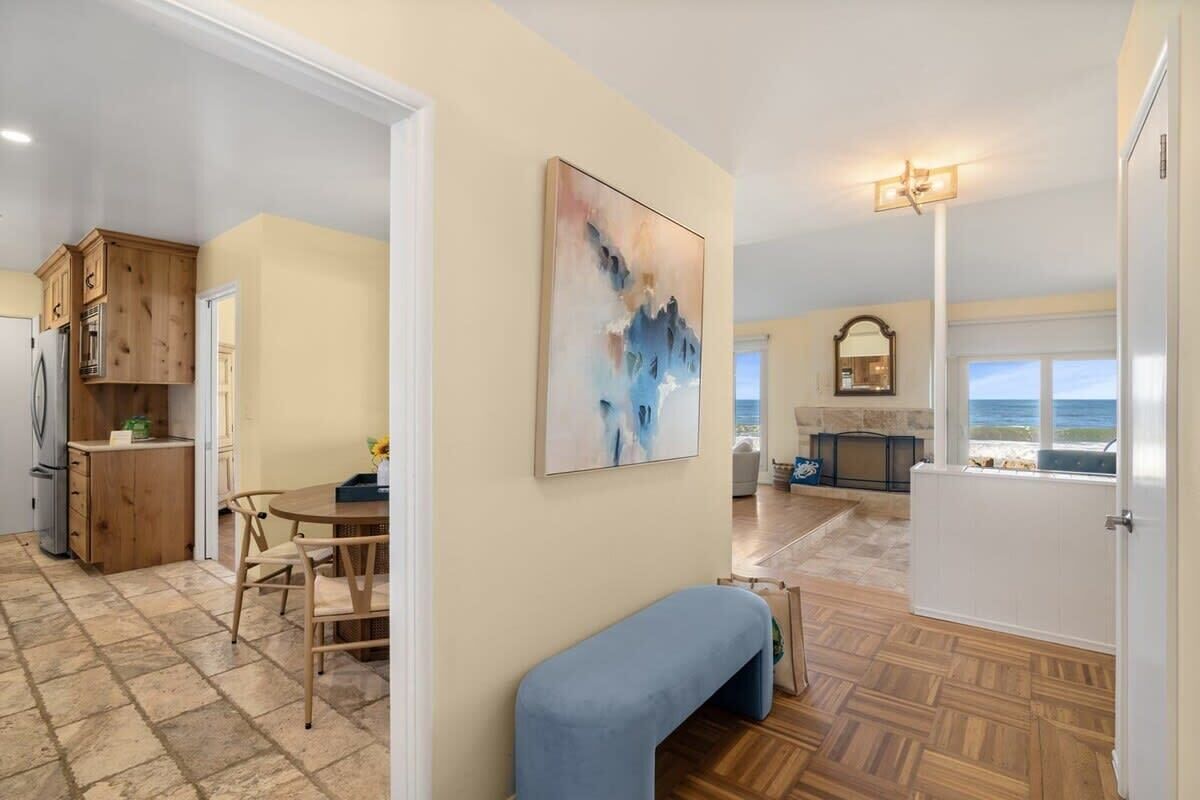 A spacious living area with a dining table and chairs, a blue bench, and a fireplace.