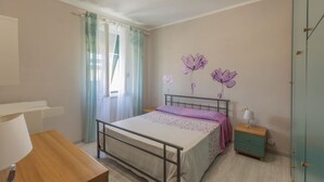Ein Schlafzimmer mit Bett, Nachttisch, Kleiderschrank und einem Fenster mit Vorhängen.