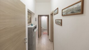 A hallway with a wooden door, a sink, and a toilet. There are framed pictures on the walls. - This beautiful and spacious apartment in Rio Marina offers all the comforts for your holiday on Elba (Rio Marina)