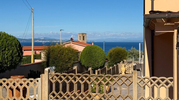 A coastal residential area with a view of the sea, a church tower, and a clear sky. - This beautiful and spacious apartment in Rio Marina offers all the comforts for your holiday on Elba (Rio Marina)