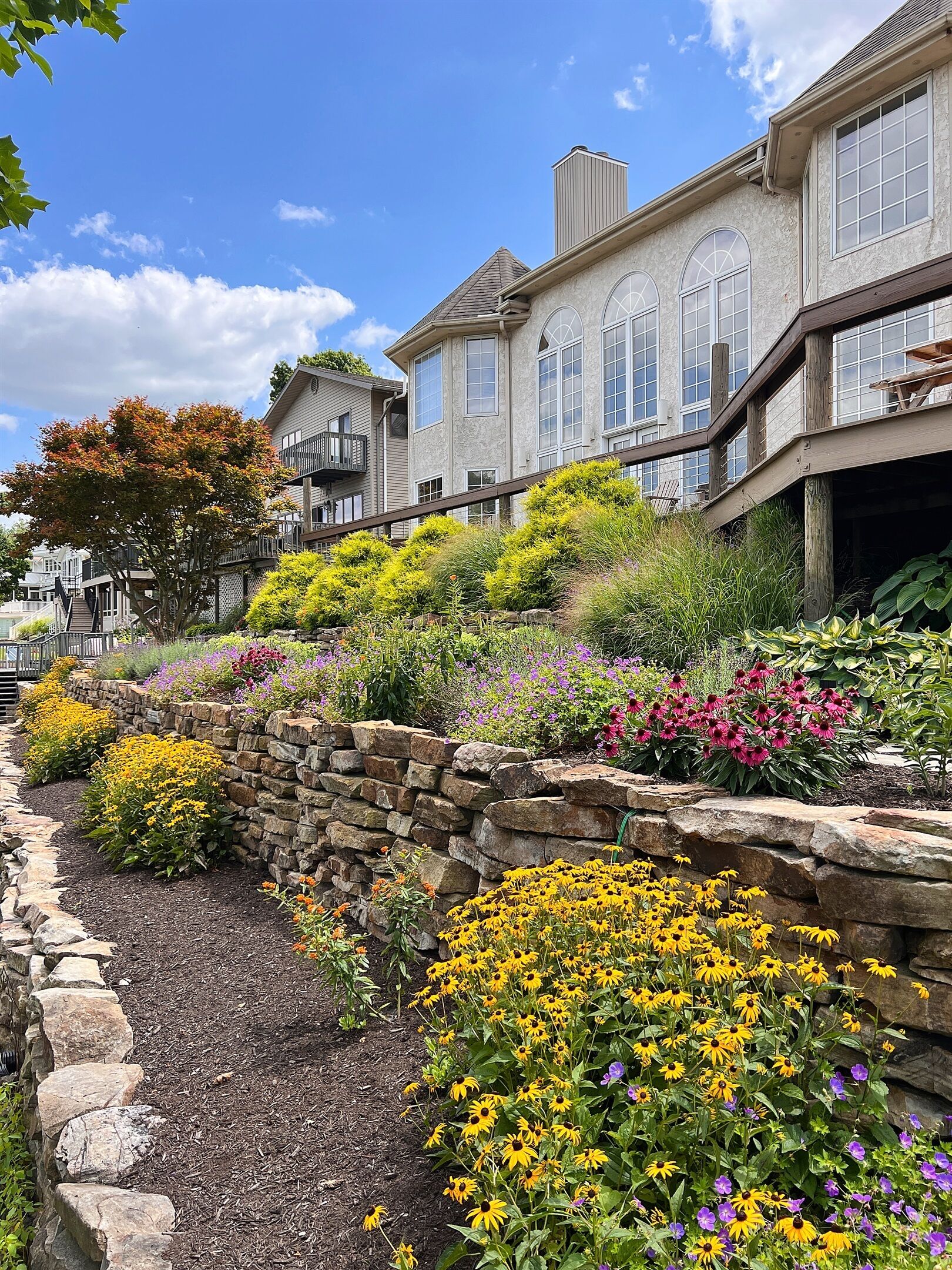 A residential area with stone walls and a variety of colorful flowers.