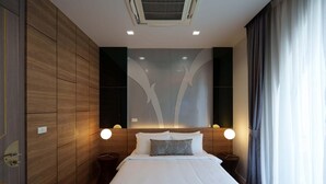 A modern hotel room with a large bed, wooden panel walls, and a decorative wall piece above the bed.