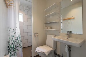 Une salle de bain équipée de toilettes, d’un lavabo, d’étagères et d’un rideau de douche.