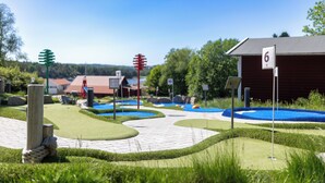 Een minigolfbaan met genummerde holes, een houten paal en een gebouw met een nummerbord.